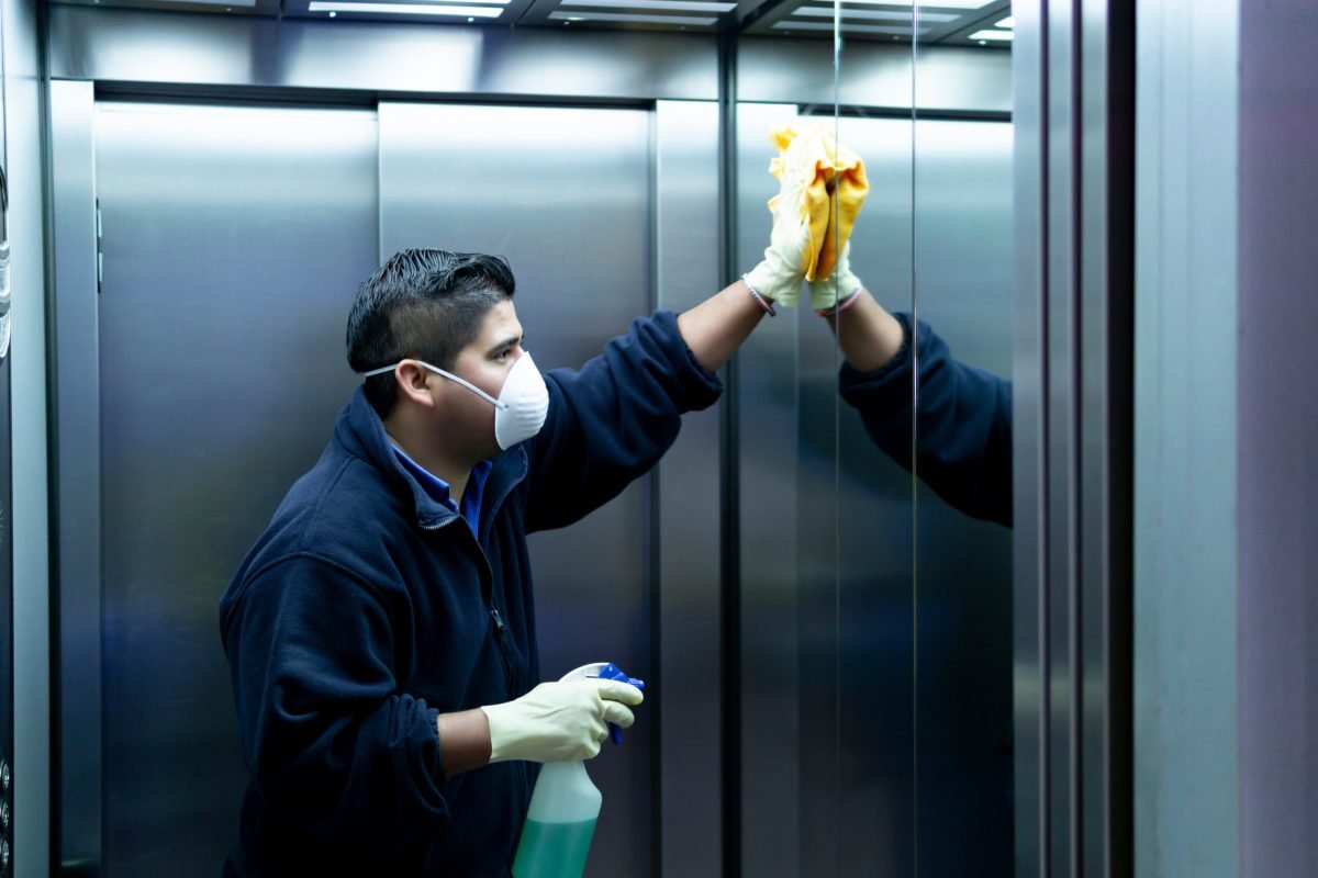 coronavirus. cleaning staff disinfecting elevator to avoid contagion